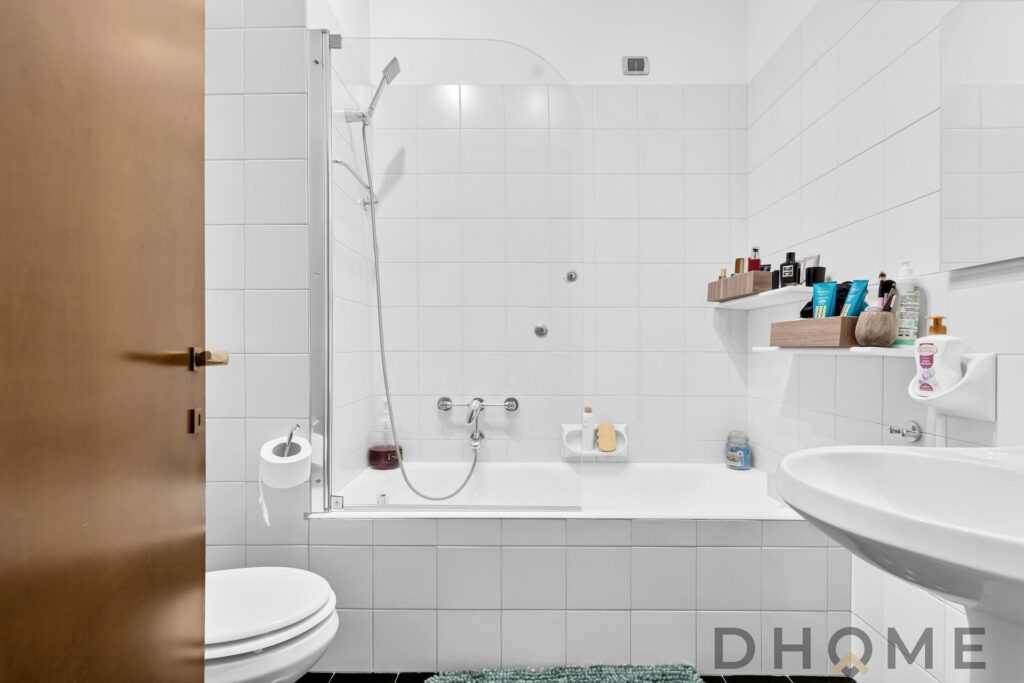 Specchio bagno con piastrelle bianche e accessori moderni.