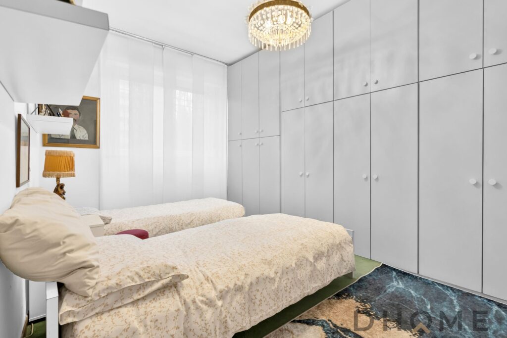 Armadio a parete bianco in camera da letto moderna con letto singolo e lampada vintage.