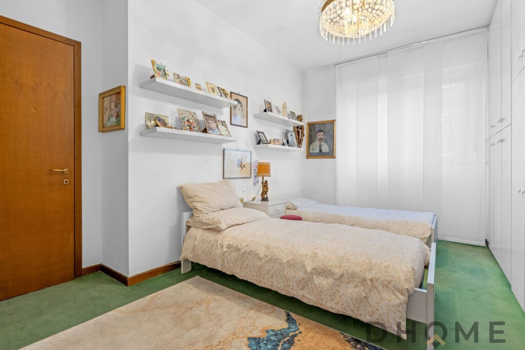 Letto matrimoniale in camera da letto decorata con quadri e oggetti d'antiquariato.