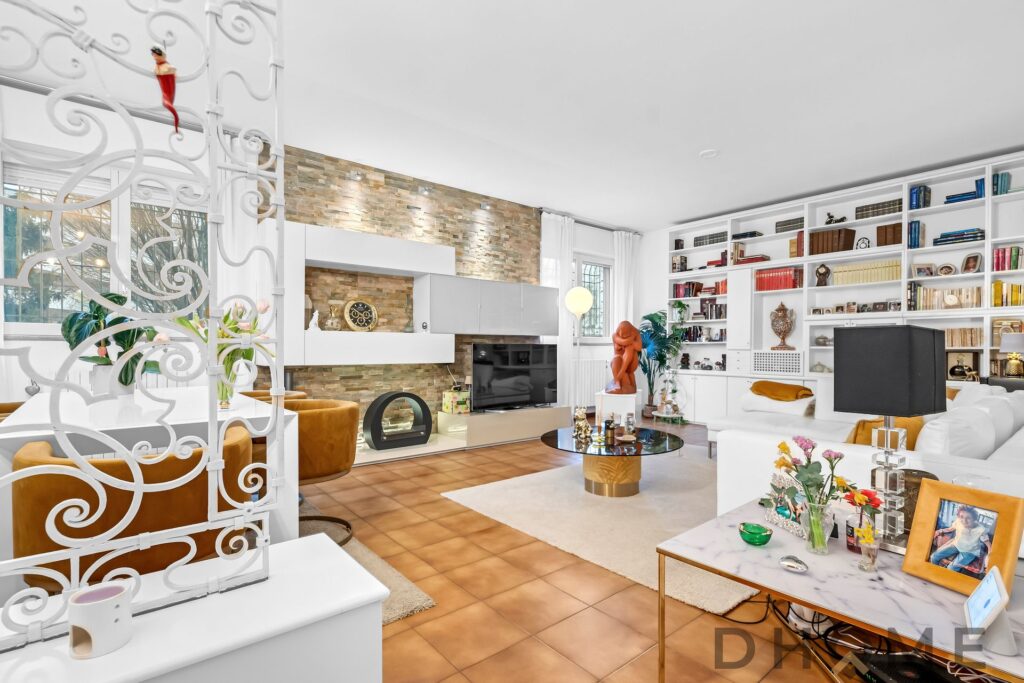 Moderno soggiorno con libreria a parete, zona relax con divano bianco e accessori di design.