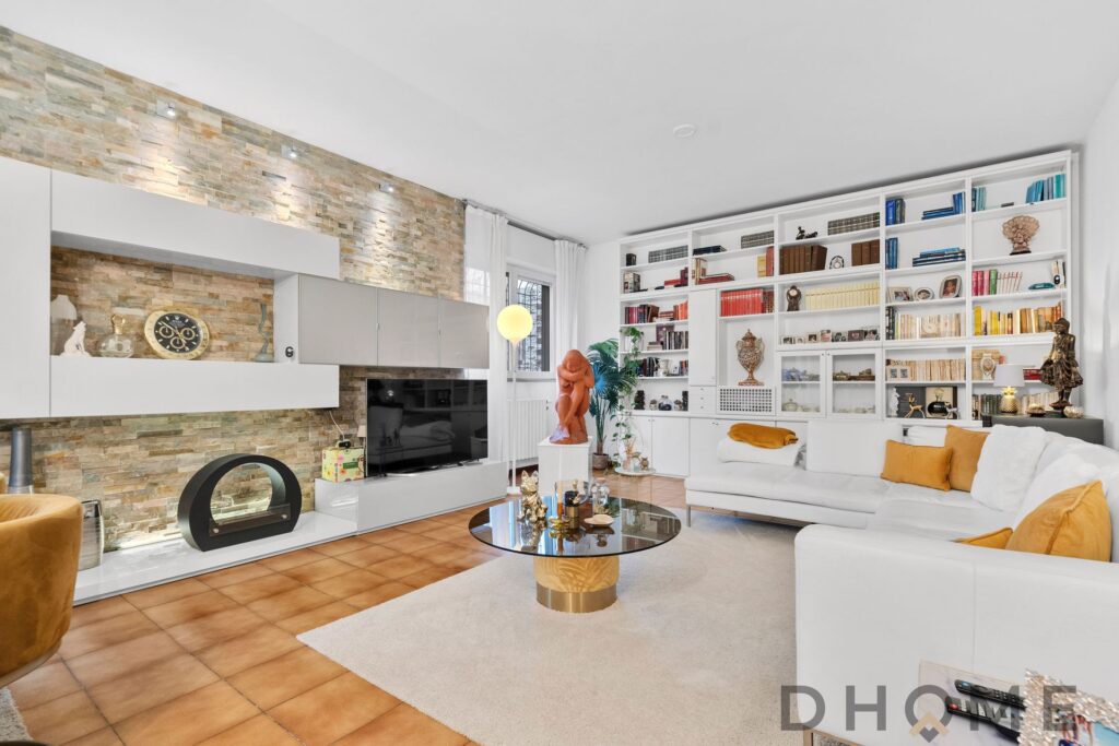 Elegante soggiorno con libreria a parete, pareti in pietra e arredi moderni, ideale per arredare la casa con stile e funzionalità.