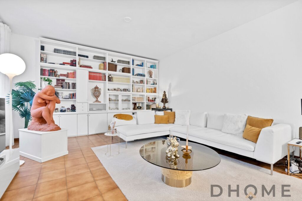 Elegante soggiorno con libreria bianca, divano bianco e arredamento moderno, ambiente accogliente e di design.