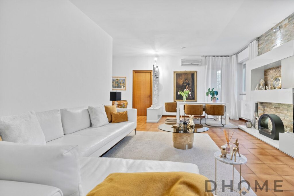 Luminosa zona living moderna con divano bianco, arredi eleganti e dettagli decorativi raffinati.