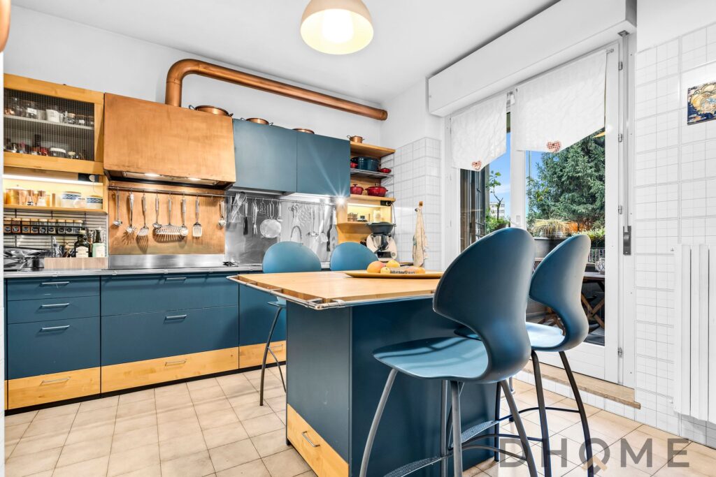 Luci naturali in cucina moderna con mobili blu e dettagli in legno. Atmosfera accogliente e funzionale per la casa.