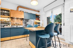 Luci naturali in cucina moderna con mobili blu e dettagli in legno. Atmosfera accogliente e funzionale per la casa.