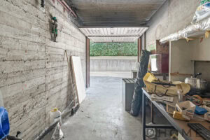 Parete in cemento armato in un garage in fase di ristrutturazione, con attrezzi e materiali da lavoro a lato.