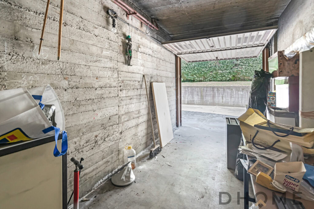 Finestra in garage con pareti in cemento grezzo, spazio di lavoro e stoccaggio.