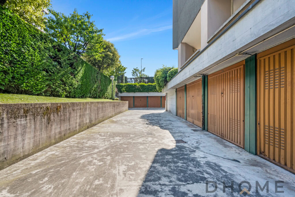 Garage con posti auto coperti e spazi di parcheggio esterni, in zona residenziale verde e tranquilla.