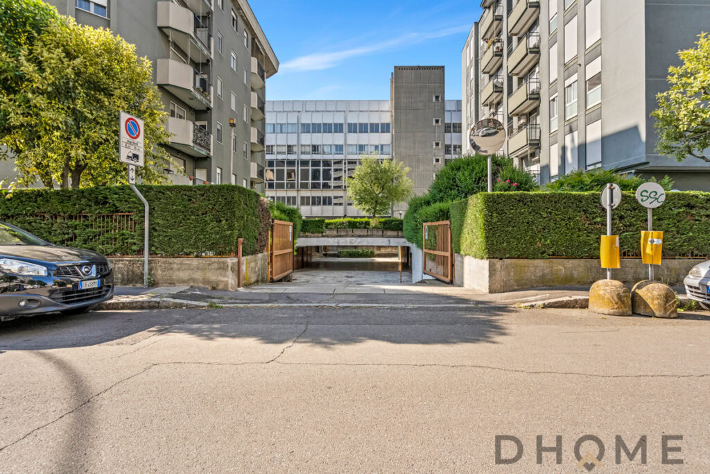 Perché nella foto si vede l'ingresso del parcheggio sotterraneo di un complesso residenziale moderno con giardini curati e automobili parcheggiate.
