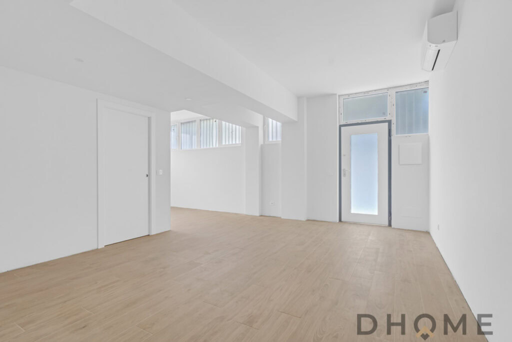 Spazio interno moderno con pareti bianche, pavimento in parquet naturale e illuminazione naturale.