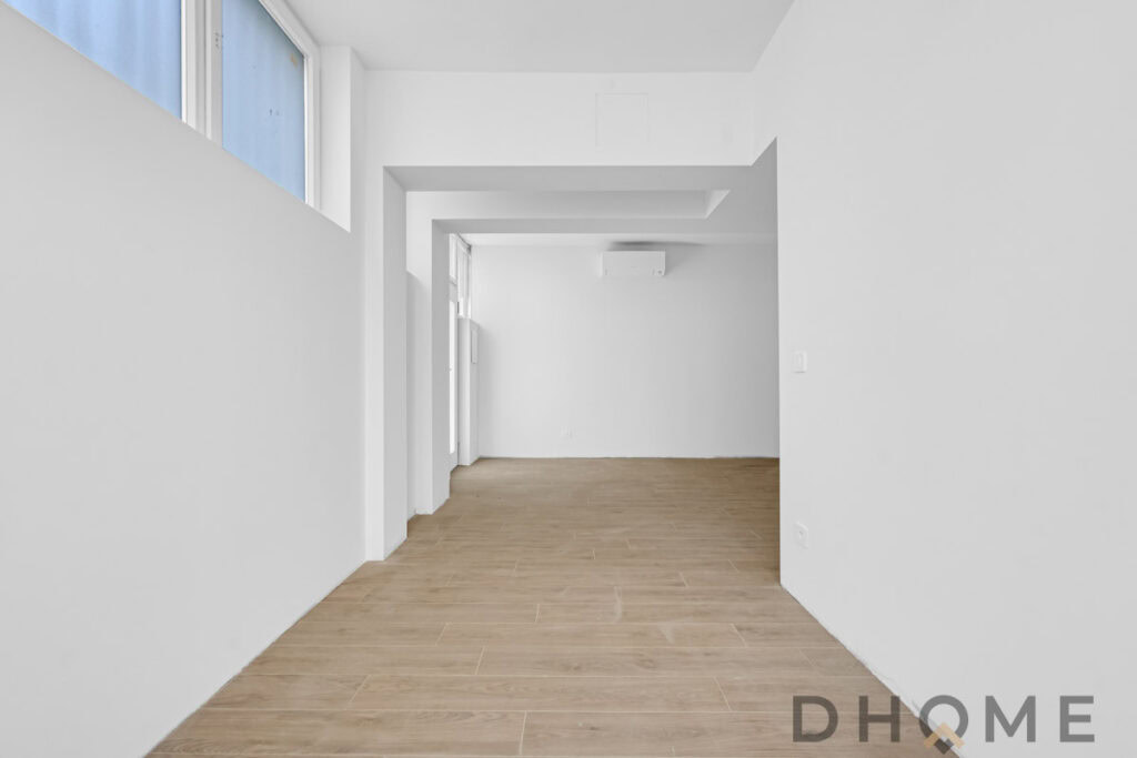 Luminoso interno moderno con pavimenti in legno chiaro e pareti bianche minimaliste, ideale per appartamenti DHOME.