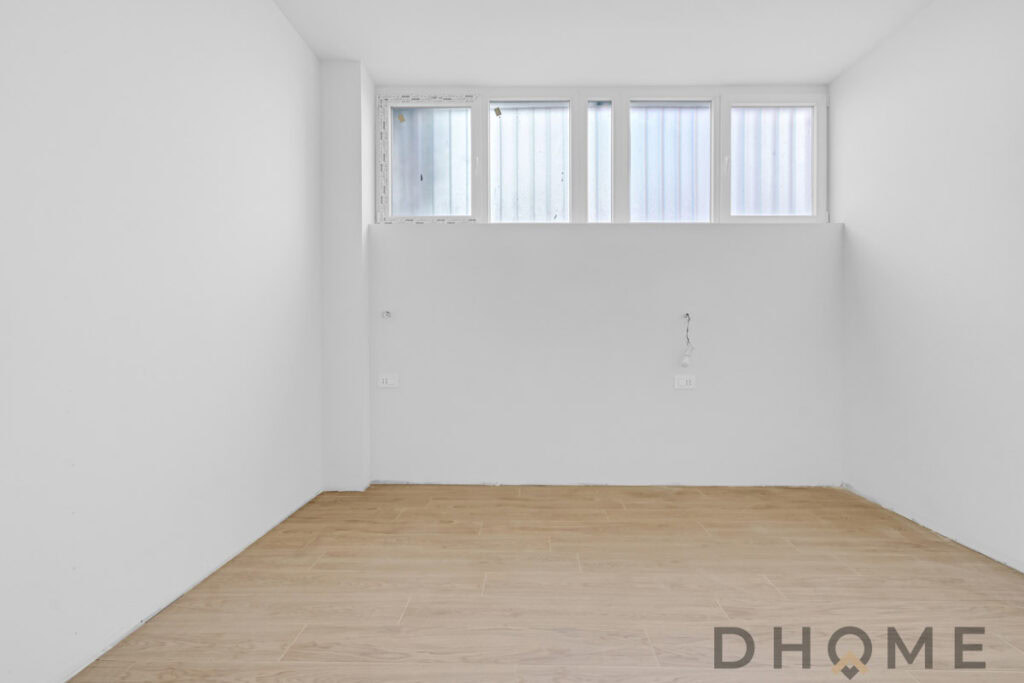 Finestra moderna e luminosa in stanza vuota con pareti bianche e pavimento in legno naturale.