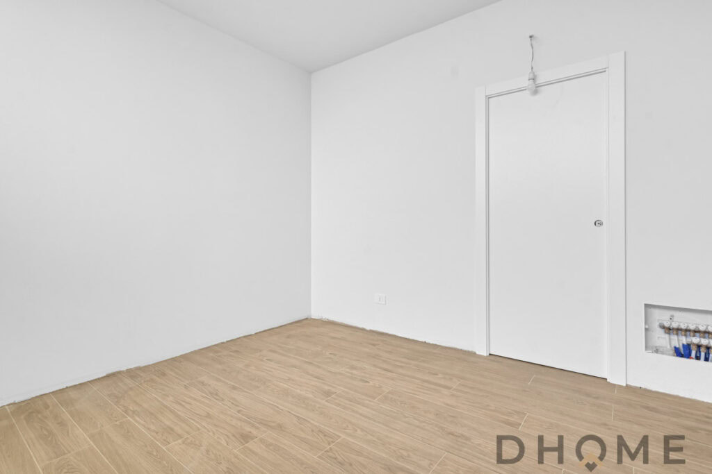 Interno di una stanza fresca con pareti bianche e pavimento in legno naturale, perfetta per ristrutturazioni e arredamento moderno.