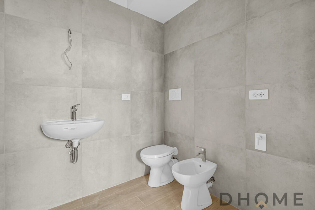 Lavandino e wc bagno ristrutturato moderno, pareti in gres porcellanato beige, impianto elettrico e idraulico installato.