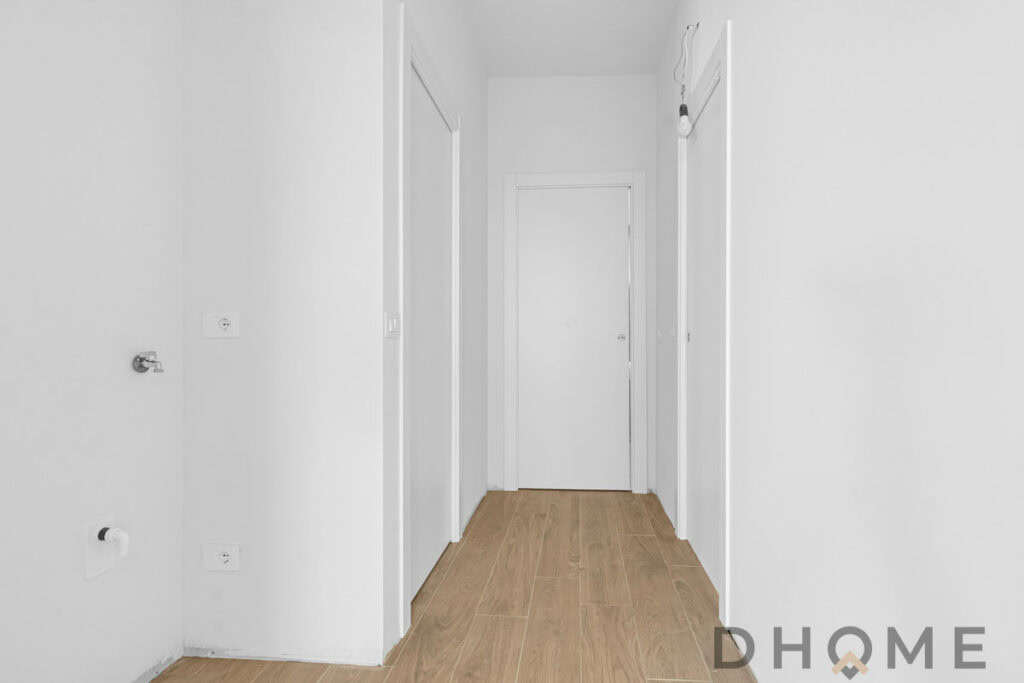 Parete bianca con porte interne e pavimento in legno chiaro, progetto di ristrutturazione DHOME.