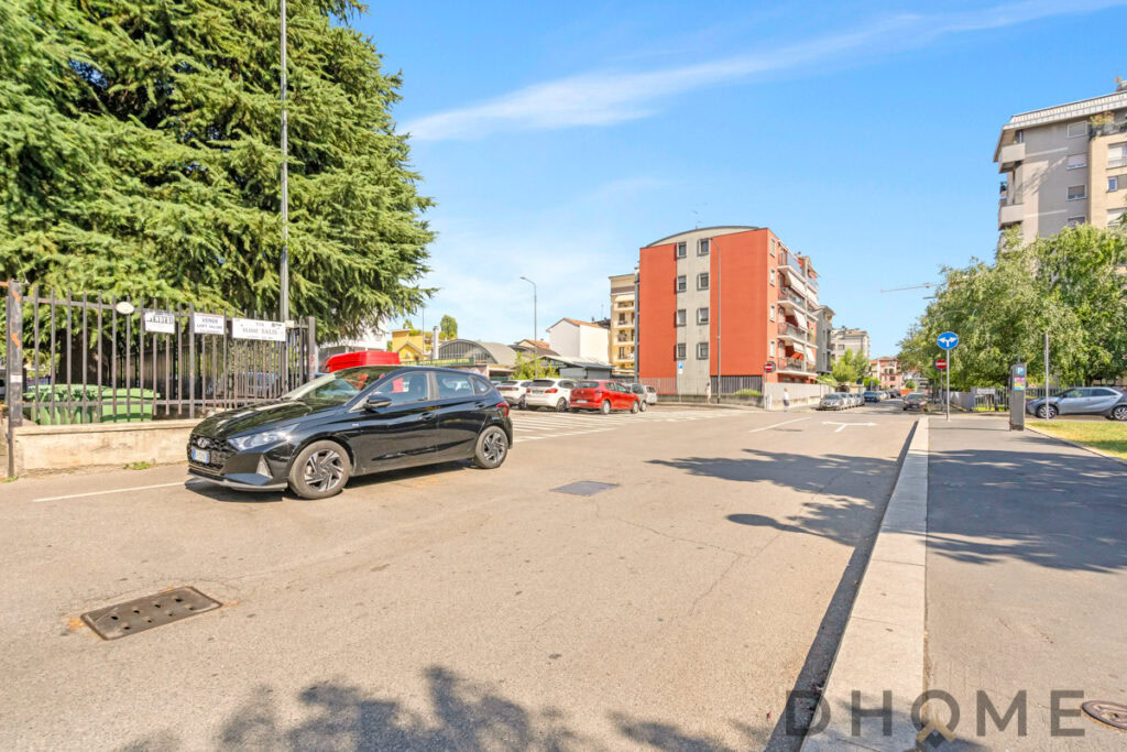 Auto parcheggiata in zona residenziale a Milano, spazio esterno e complesso di appartamenti in background.