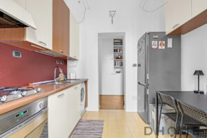 Cucina moderna con frigorifero, piano cottura e armadietti, ambiente funzionale e luminoso.