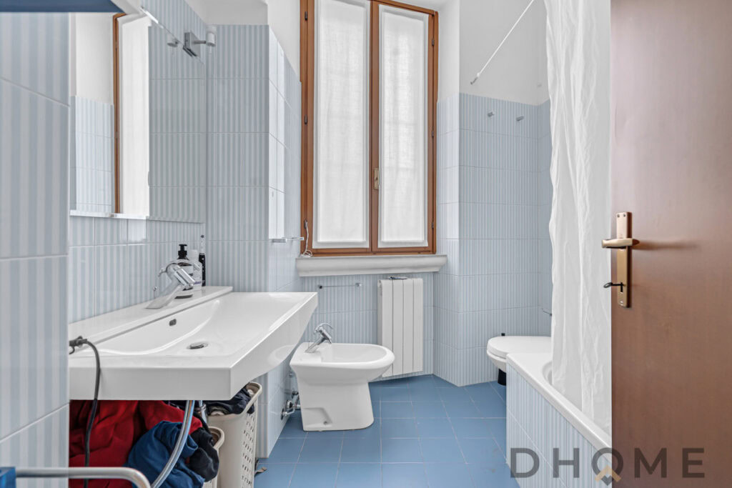 Lavabo con specchio e finestra in bagno ristrutturato.