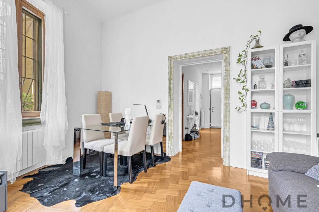 Elegante sala da pranzo con tavolo in vetro e sedie beige, luce naturale e arredi moderni.