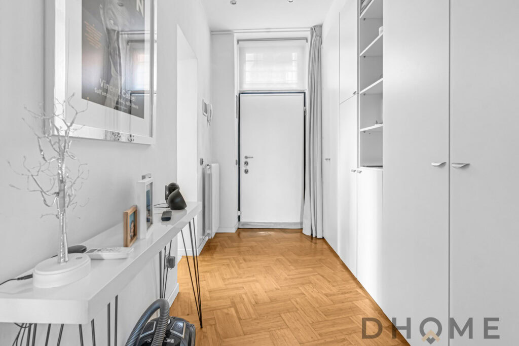 Porta d'ingresso moderna con armadiature bianche e pavimento in parquet, design minimalista e funzionale.
