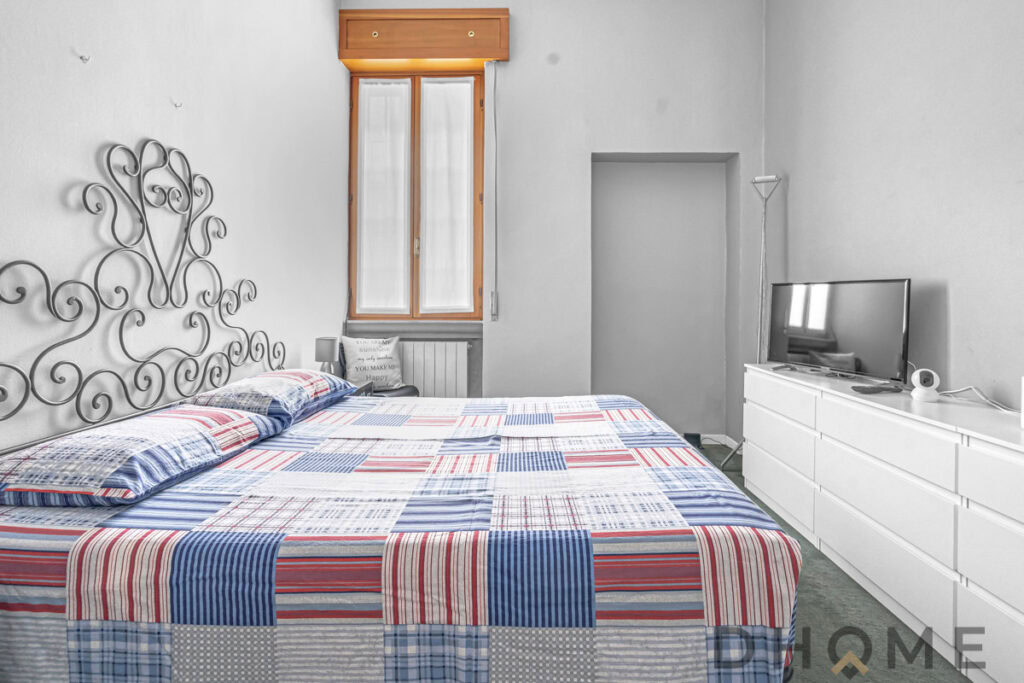 Letto con testiera in ferro battuto e stanza luminosa con finestra, arredamento moderno e confortevole.