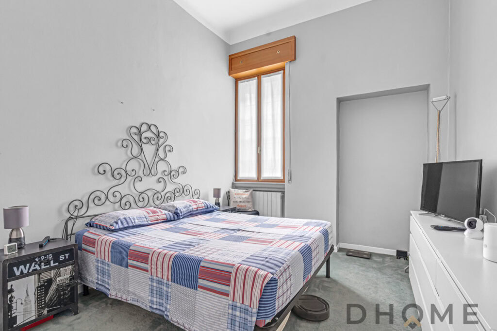 Letto matrimoniale con parete decorativa in metallo, finestra luminosa in camera da letto.