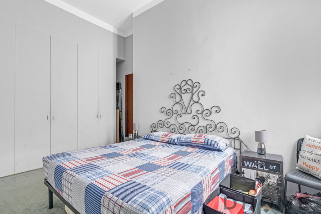 Letto matrimoniale in camera da letto con testiera in ferro battuto, arredamento semplice e funzionale, spazio di riposo e relax.