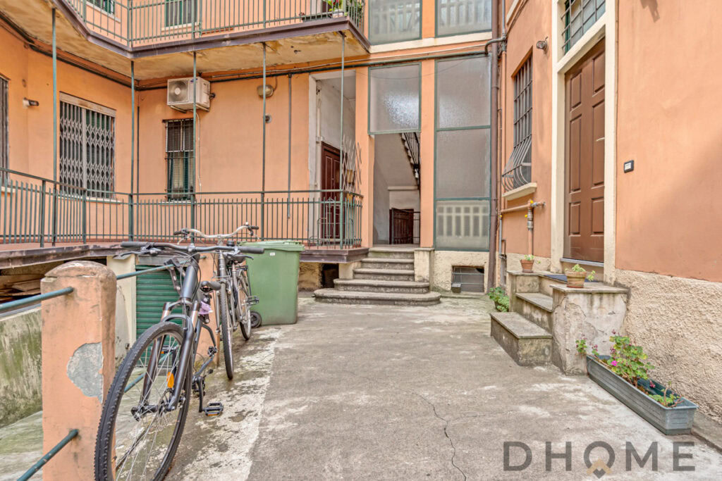 Cortile condominiale con biciclette e piante in vaso.