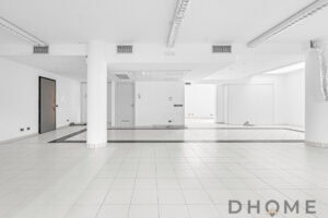 Spazio commerciale vuoto con pavimenti in ceramica e pareti bianche dalla luce naturale.