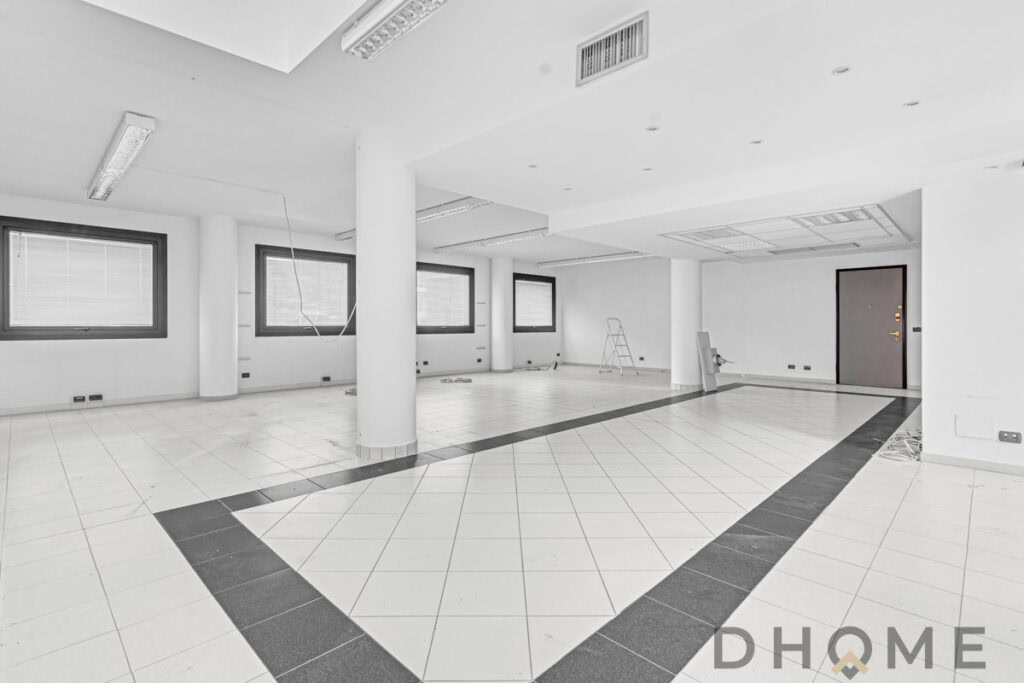 Spazio ufficio ristrutturato con grandi finestre e pavimento in piastrelle.