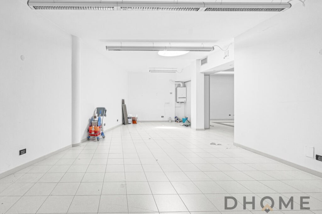 Spazio commerciale vuoto in fase di ristrutturazione, interni moderni, pavimenti in gres porcellanato, luce naturale, servizi di edilizia DHOME.