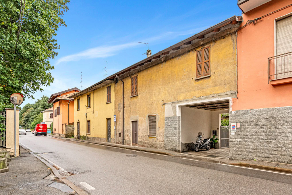 Dettaglio strada residenziale con edifici colorati e scooter parcheggiato sotto portico.