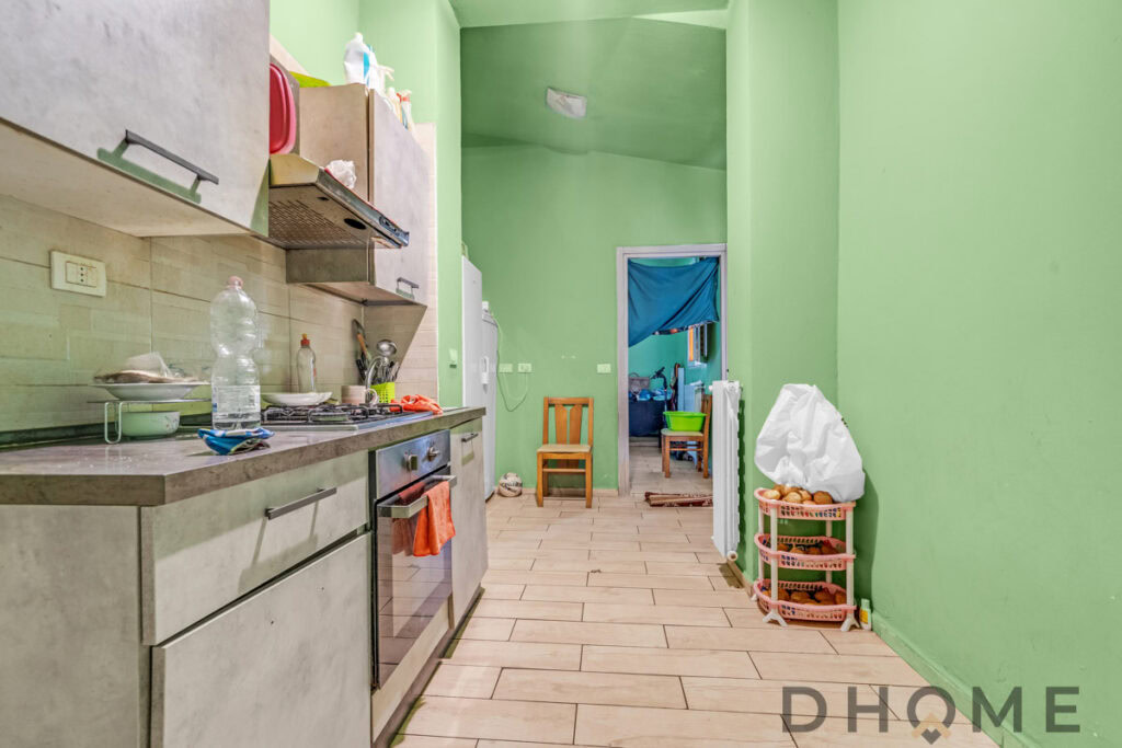 Lavanderia con cucina a vista, pareti verdi e arredi pratici. Ideale per vivere in modo funzionale e confortevole.