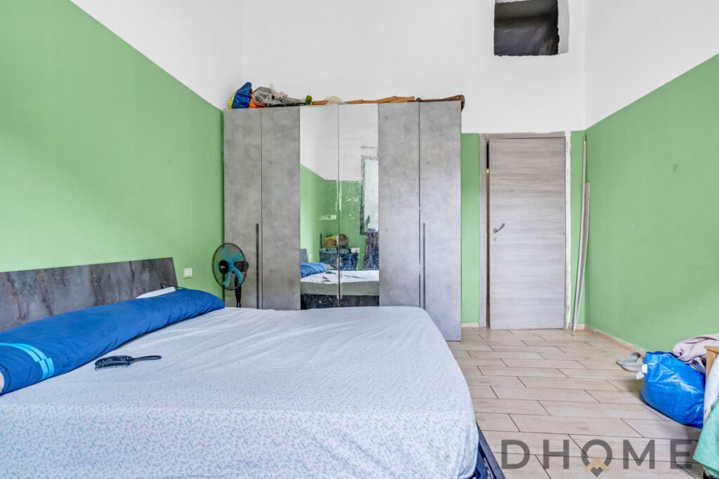 Armadio con specchio e letto matrimoniale in una stanza in corso di ristrutturazione.