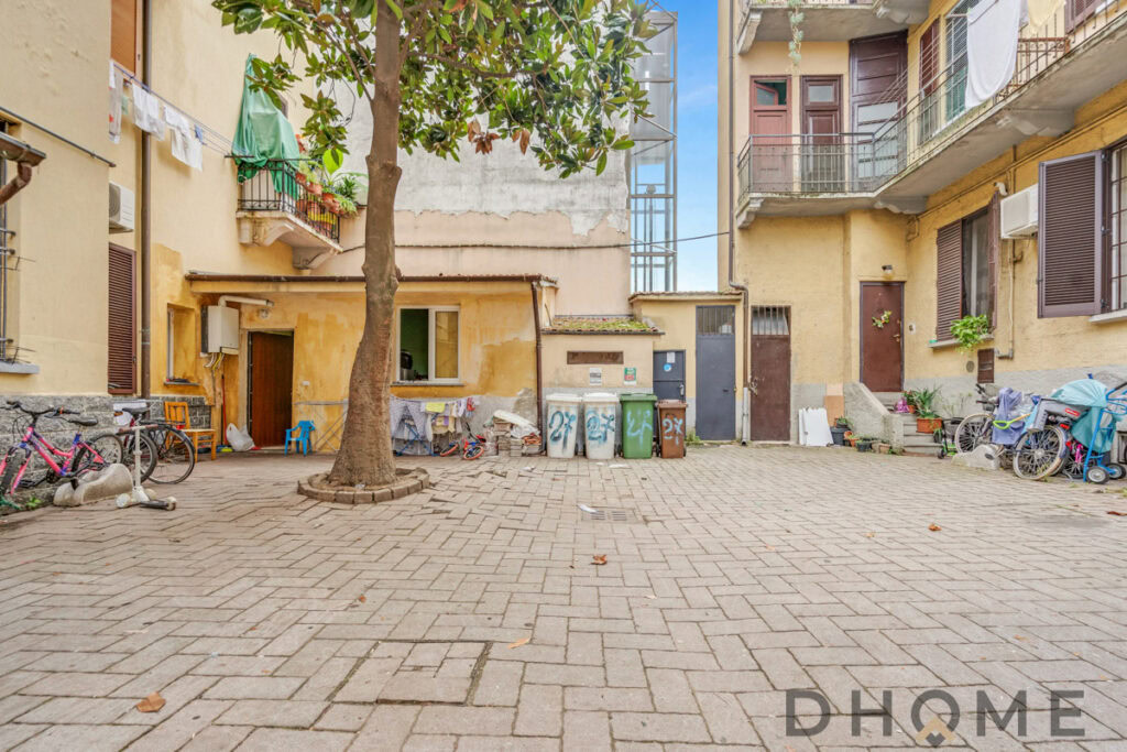 Pozzo con bicicletta e piante, cortile condominiale in zona urbana, edificio residenziale in Italia.