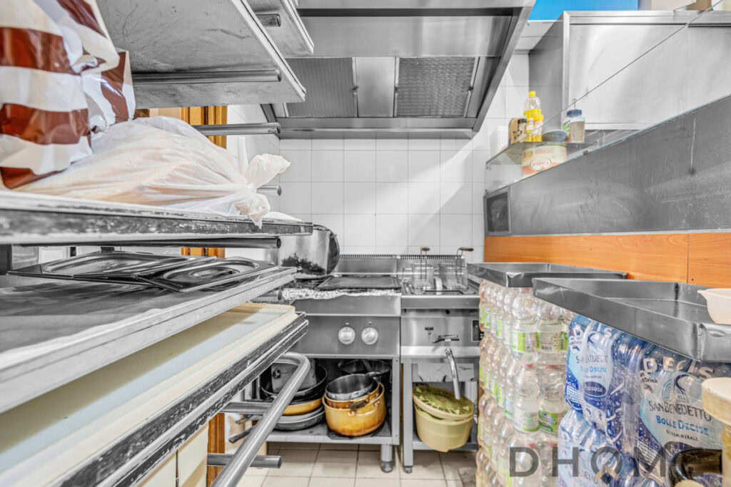 Deposito di cucina professionale con attrezzature in acciaio inox e scaffalature industriali.