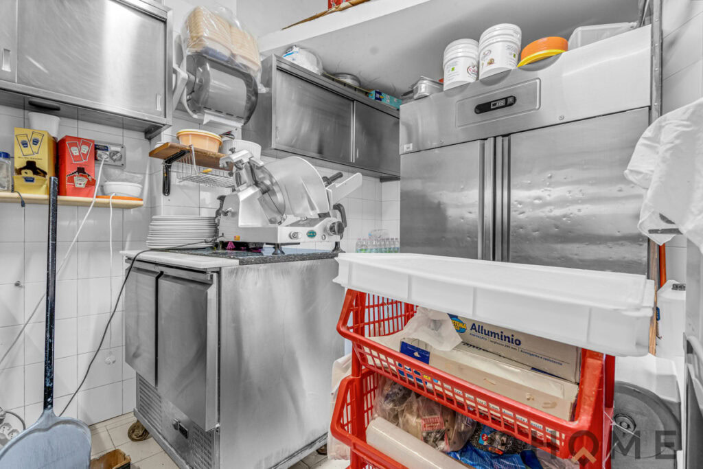 Doccia a taglio su attrezzature da cucina in un laboratorio alimentare professionale, con superfici in acciaio inox e scaffali.