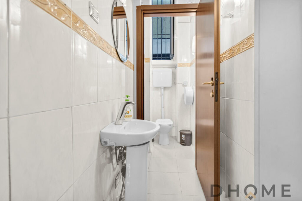 Lavabo e bagno in muratura con sanitari moderni e rivestimenti chiari in ceramica.