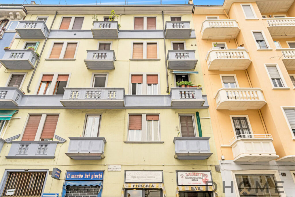 Balconi con ringhiera in cemento color grigio su edificio residenziale a Milano, vista strada.