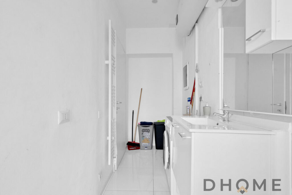 Lavanderia moderna bianca con lavatrice e attrezzi per la pulizia.