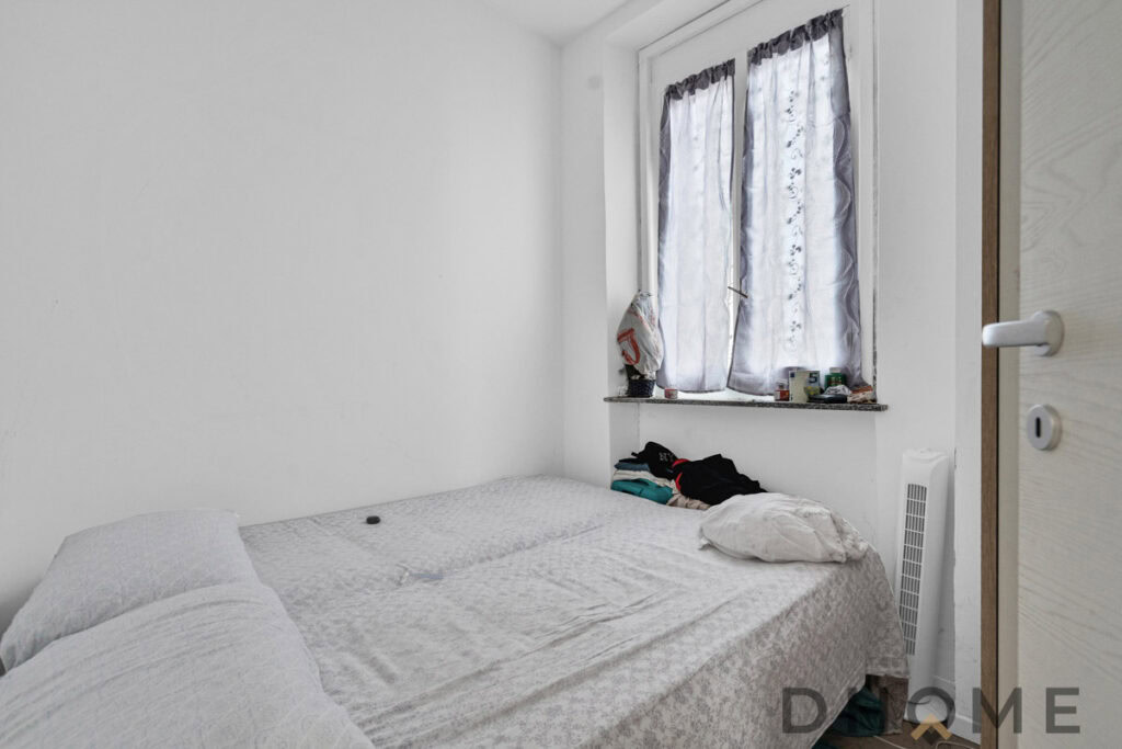 Stanza da letto semplice con finestra e arredi minimalisti, ideale per case e appartamenti moderni.