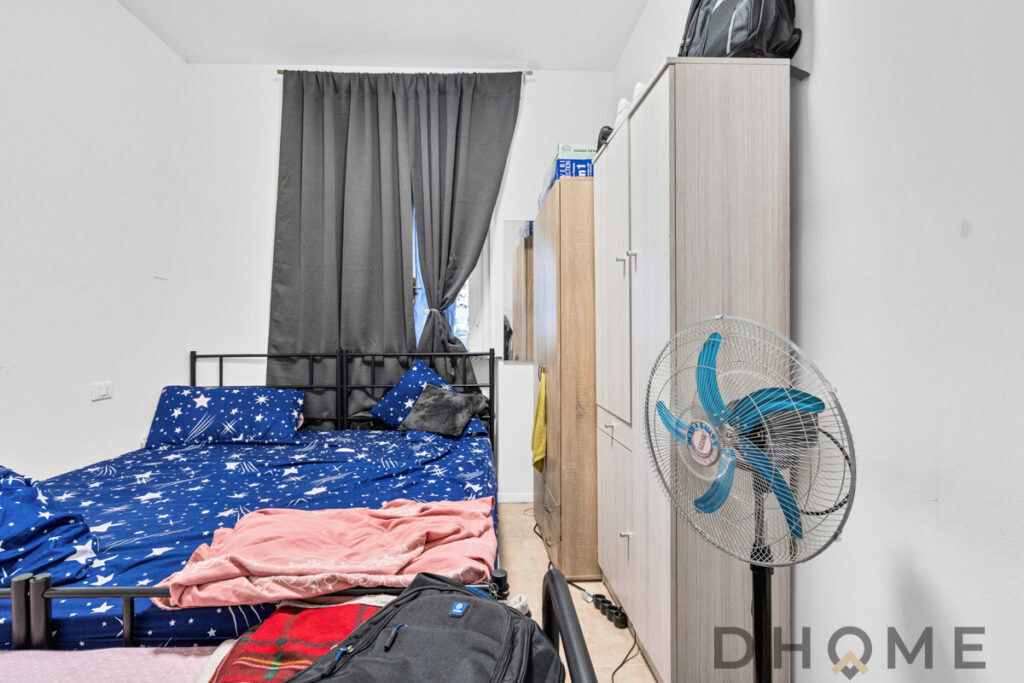 Letto matrimoniale con biancheria azzurra con stelle, armadi e ventilatore in camera da letto.