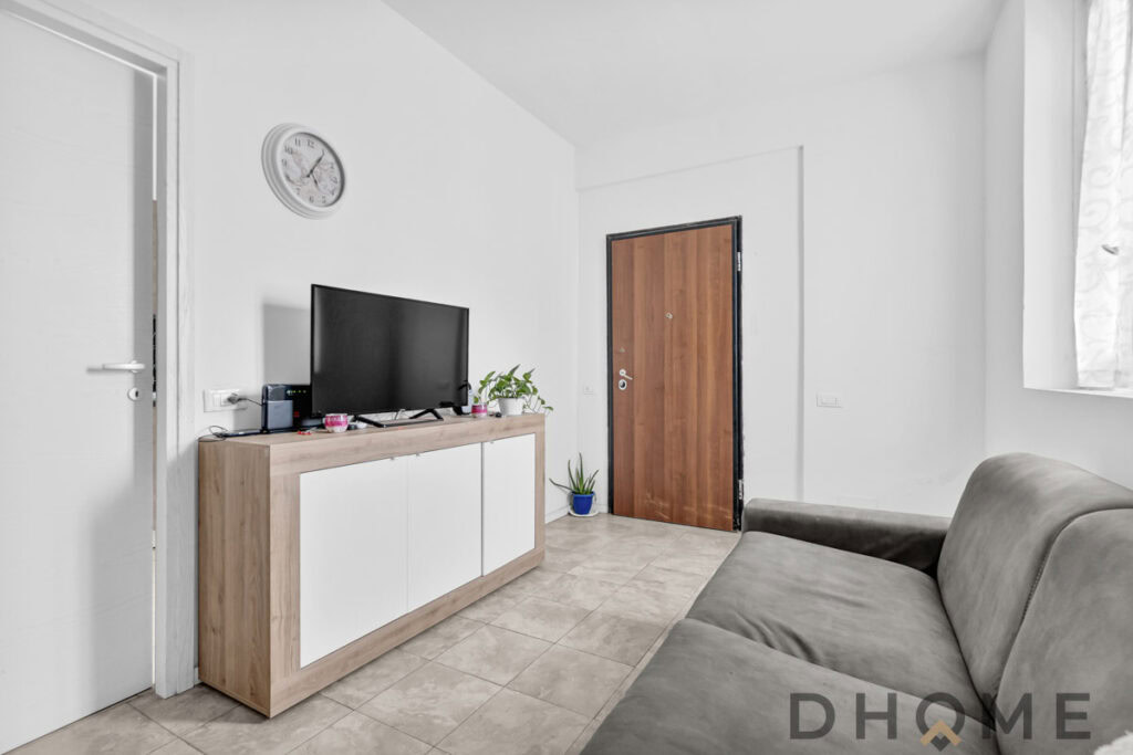 Apparecchiatura TV moderna in soggiorno con mobili in stile minimalista, piante decorative e pareti bianche eleganti.