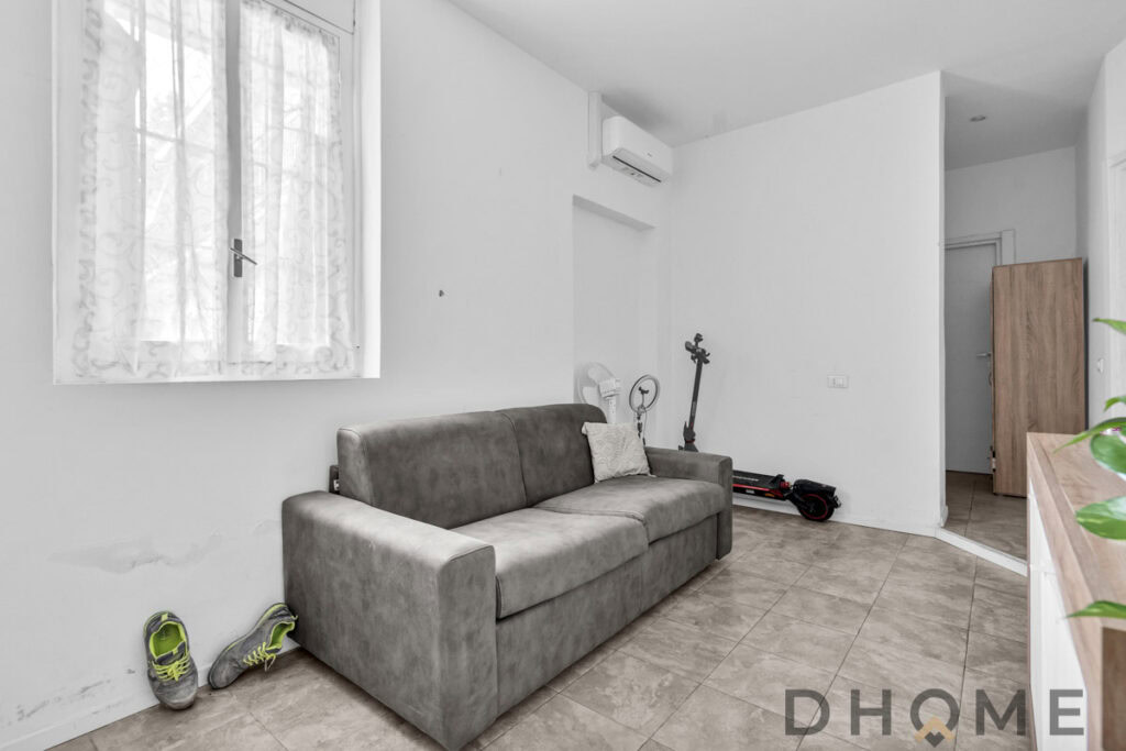 Soggiorno minimalista con divano grigio e area relax moderna.