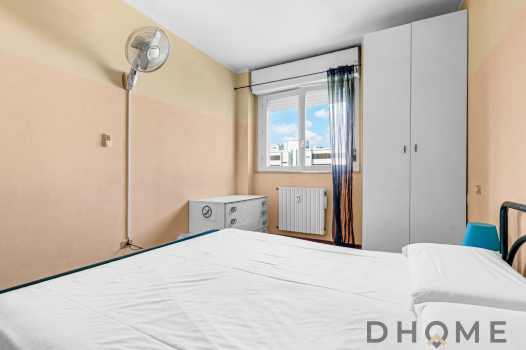 Letto matrimoniale in camera con aria condizionata e finestra con vista città.