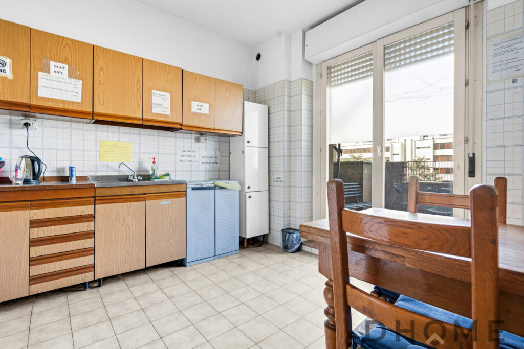 Lavanderia cucina con mobili in legno e balcone con vista città.