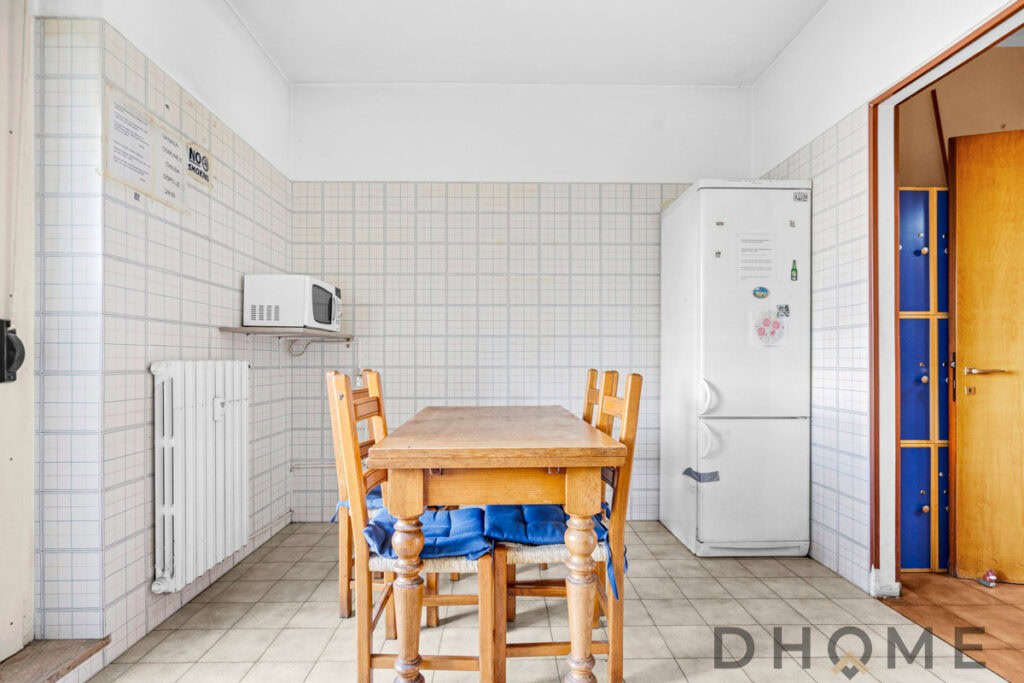 Axaltino cucina con tavolo in legno e frigorifero in ambiente domestico, stile semplice e funzionale.