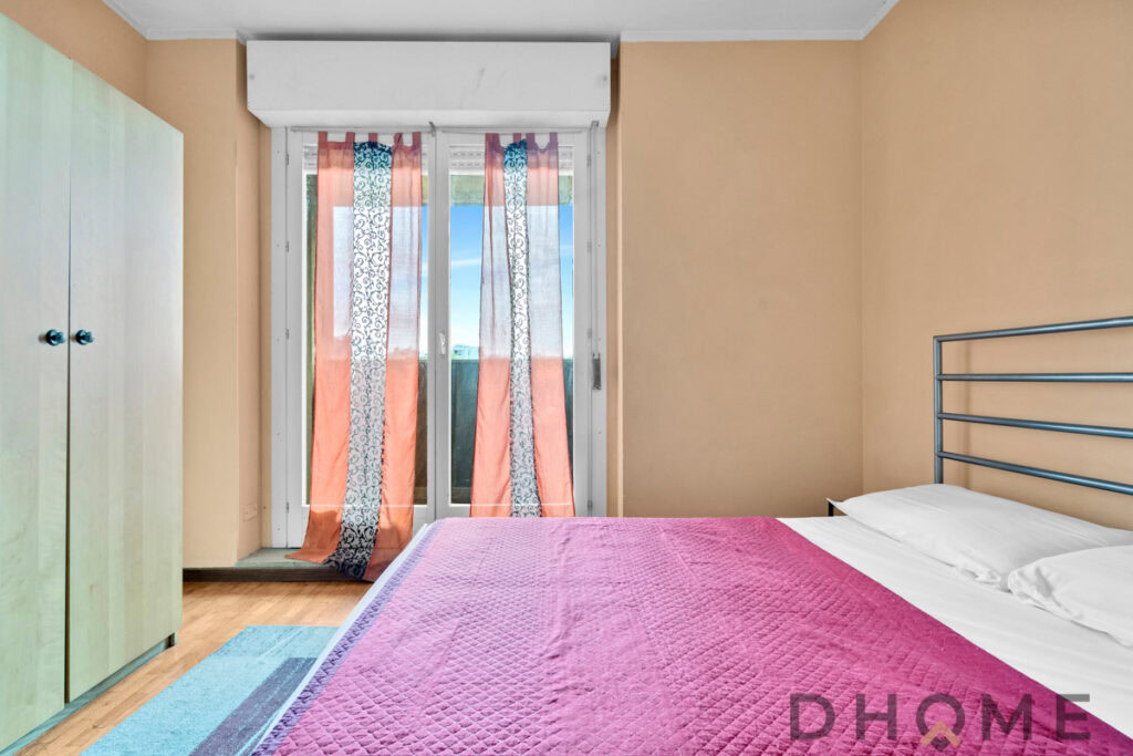 Camera da letto, arredamento semplice e luminoso, balcone con tende colorate, stile minimalista, DHOME arredamenti casa e soggiorno.