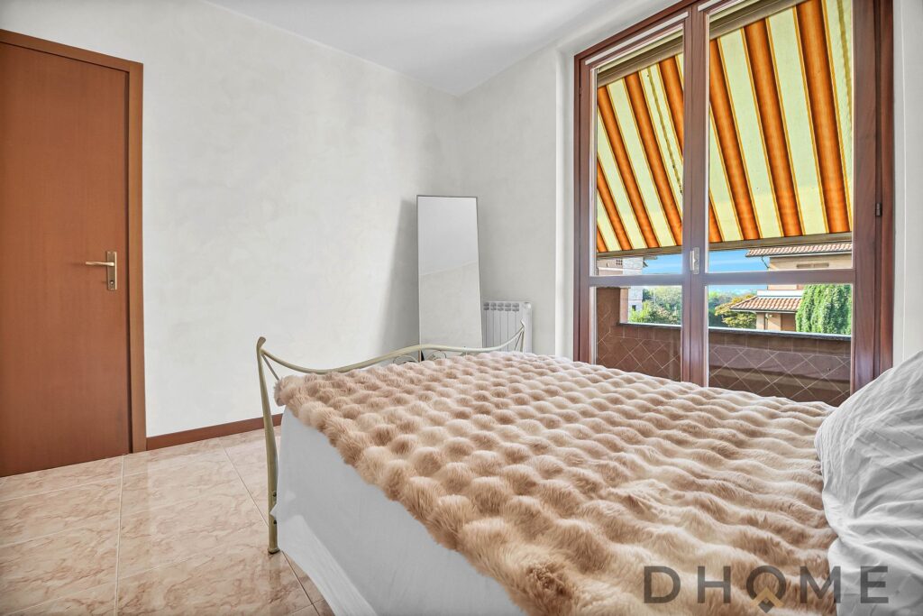 Letto matrimoniale con coperta peluche in camera luminosa e spaziosa.