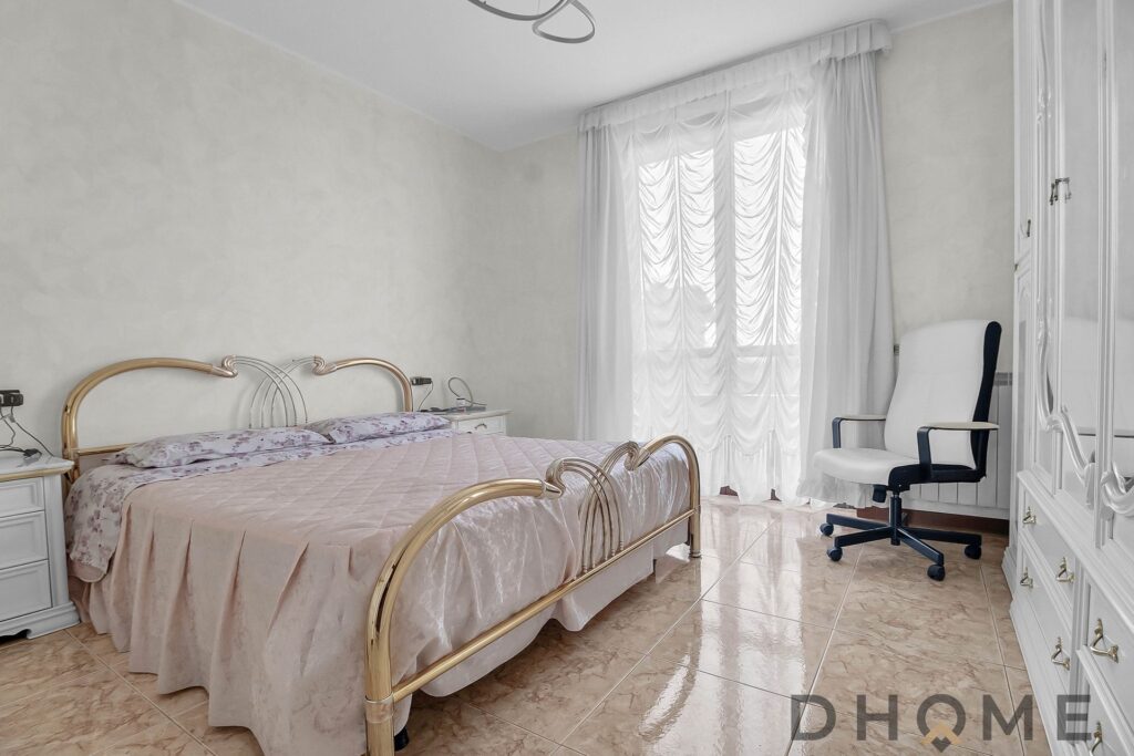 Lettino matrimoniale con testiere in metallo dorato e arredi bianchi eleganti in camera da letto.